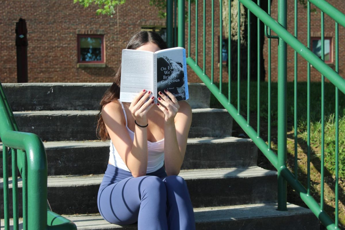 Student reads book on stairs completely engaged in the novel. On Earth Were Briefly Gorgeous is the perfect spring to summer read. 