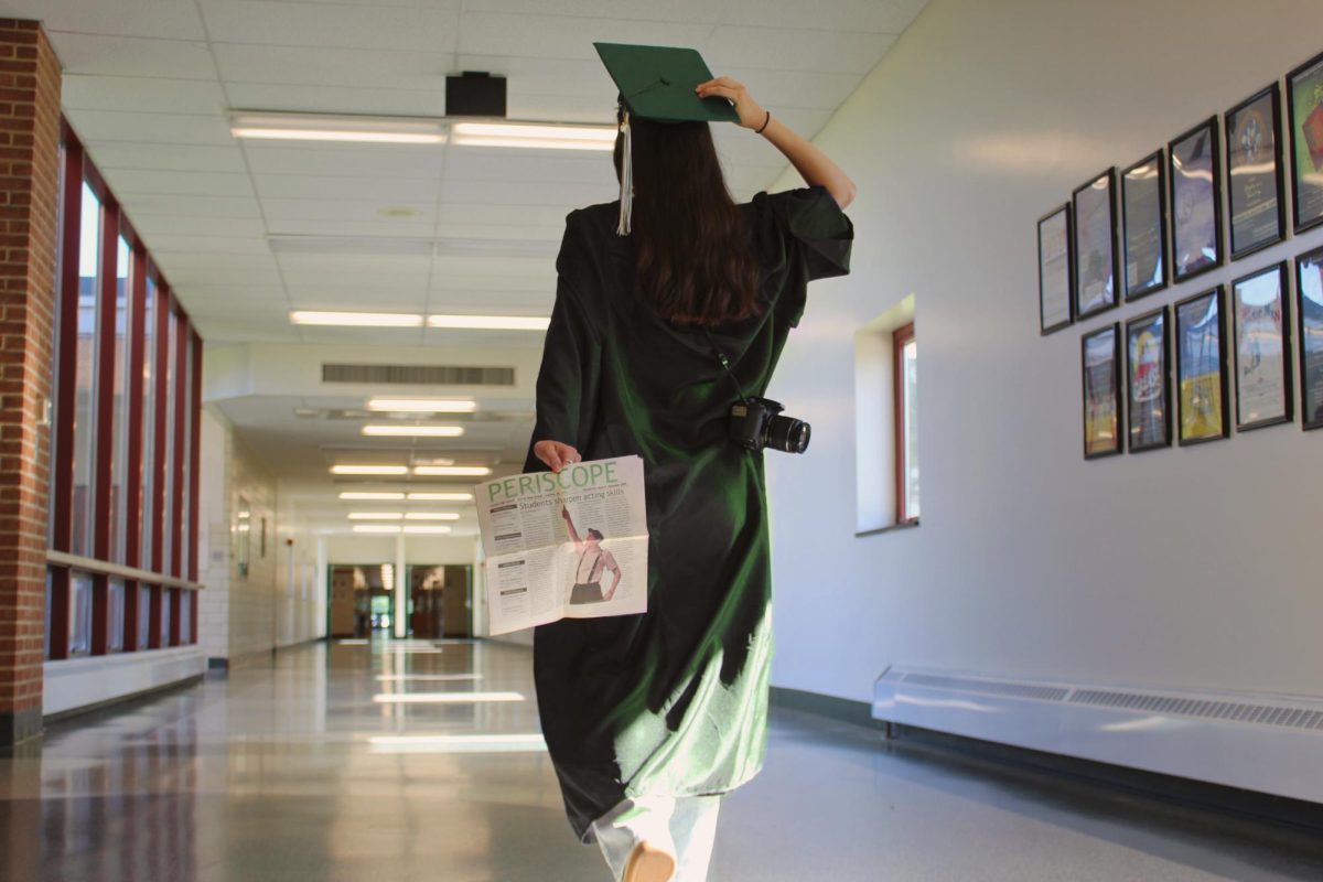 Scarlett Learned walks out of CHS halls in her cap and gown with Periscope equipment; the beloved camera, and our printed news articles. 